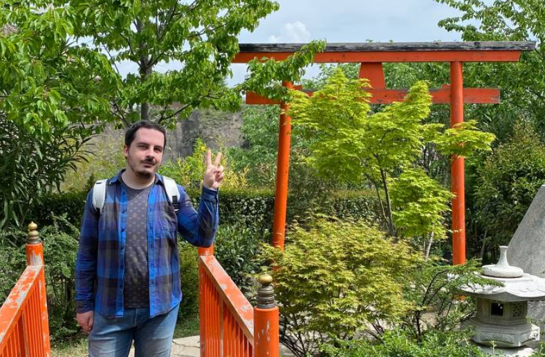 Stas Pogorskii posing awkwardly in a Japanese-themed garden